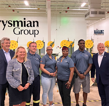 A group of people gathered together inside a room to celebrate Prysmian Group