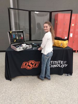 Photo of Tonya Felsinger with her field work tools in front of a table with a cover saying Institute of Technology