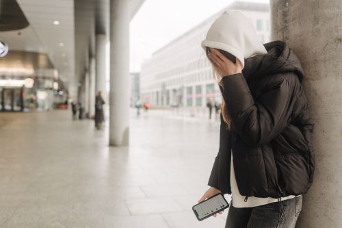 Upset and depressed girl holding smartphone and holding head. Lonely bullied teen
